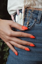 Bright neon manicure on female hands on the background of jeans. Nail design. Beauty hands