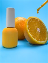 Bright bottle of nail polish on a blue background with orange fruits. Manicure design