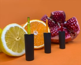 Black bottles of nail polish on a orange background with fruits. Manicure design