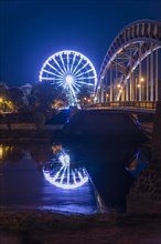 Illuminated Ferris wheel reflected in Elbe