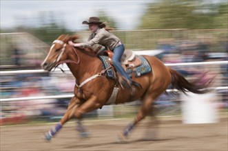 Motion blur of a cowgirl riding fast during barrel racing