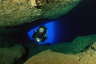 Diver sport diver swims in illuminated cave underwater cave