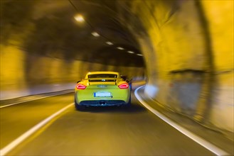 Speeder in sports car Porsche speeds through bend in winding tunnel