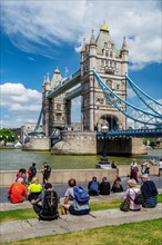 Tourists on the banks of the Thames with Tower Bridge