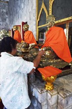 Believers cover statues of monks with gold leaf