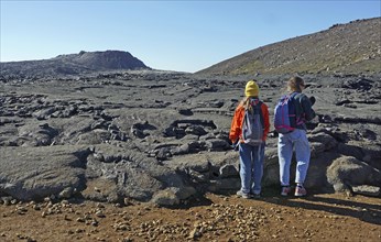 Women hikers standing in front of solidified lava