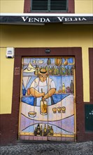 Colourfully painted door with bartender preparing poncha