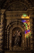 Coloured light on a gilded side altar with Christian figures
