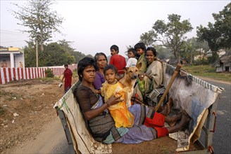 Villagers traveling on a bullock cart with their pet dog