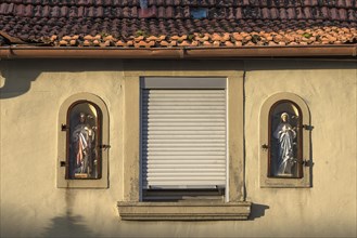 Figures of saints on a house facade in niches behind glass