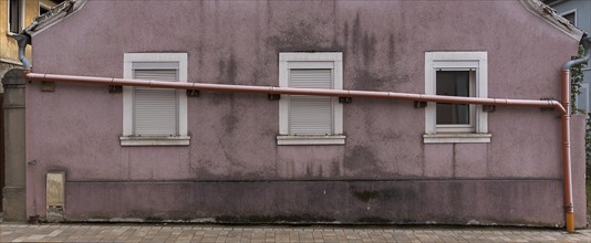 Drain pipe runs across the windows of a single-family house