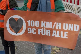Climate activist of the group Letzte Generation holds poster for speed 100 and 9 euro ticket