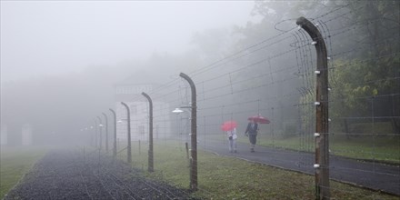 Reconstructed camp fence with people in the fog at beech forest concentration camp