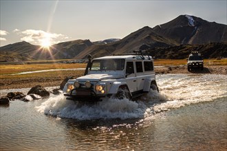 Two off-road vehicles ford a river in Iceland