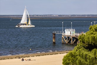 Sailboat in front of jetty and beach in Arcachon