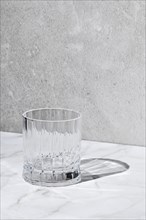 Empty facetted glass over grey background