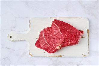 Top view of raw top side beef steak on marble background