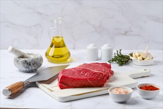 Raw top side beef steak with spice and herbs on kitchen table