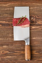 Piece of raw beef eye of round steak on butcher's cleaver with place for text