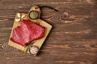 Overhead view of raw top side beef steak on wooden tabletop with place for text
