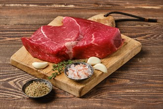 Fresh raw top side beef steak on wooden cutting board ready for barbeque