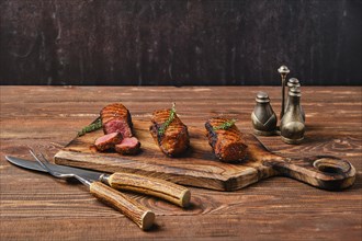 Grilled beef brisket flat steaks on wooden serving board