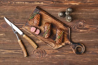 Top view of grilled beef brisket flat steaks on wooden serving board