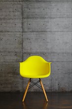 Yellow plastic modern design armchair on wooden stands