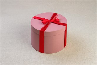 Round pink giftbox with red ribbon