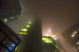 Illuminated skyscrapers in the fog at night