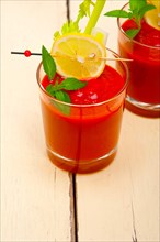 Fresh tomato juice gazpacho soup on a glass over white wood table