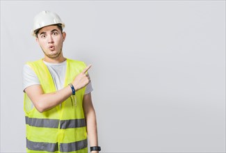 Surprised face construction worker pointing at an advertisement. Engineer man pointing to side. Surprised face engineer pointing finger to the right