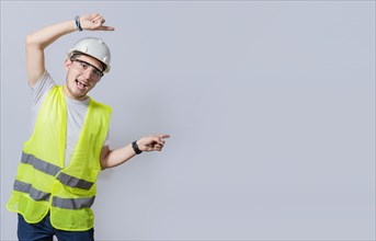 Construction engineer with vest pointing at an advertisement. Engineer man pointing to side. Smiling engineer man pointing aside