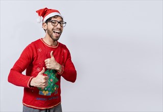 Happy young man in christmas hat giving thumbs up. People in santa hat doing ok gesture. Concept of christmas man giving thumbs up