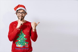 Man in Christmas sweater in silence gesture pointing to the side