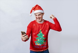 Teenager in christmas hat celebrating a promotion with the cell phone
