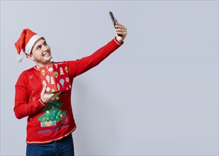 Christmas handsome man taking a selfie holding a gift isolated. Happy guy taking a christmas selfie isolated