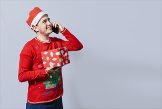 Christmas man holding gift and calling family on phone. Happy man holding gift and calling family at christmas