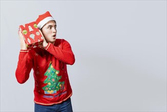 Christmas guy holding and listening a gift box. Excited christmas people holding and listening a gift. Concept of guessing a christmas gift