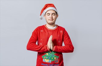 Guy with hands together praying in christmas isolated