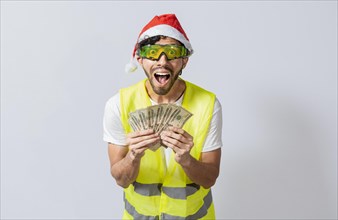 Engineer in christmas hat holding money smiling at camera. builder engineer in christmas hat with happy expression holding dollars isolated. Concept of engineer with money in holiday season