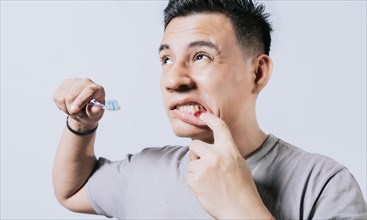 Man holding toothbrush with gum pain isolated