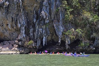 Tourists explore eroded limestone cliffs by canoe in Phang Nga Bay