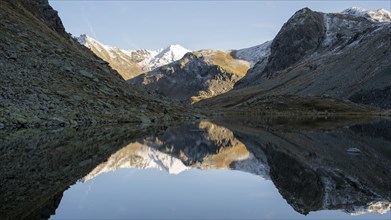Slightly snow-covered mountains reflected in Schwarzsee in autumn on the Flueela Pass