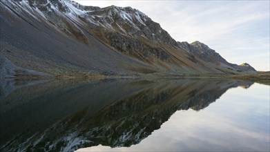 Slightly snow-covered mountains reflected in Lake Schotten in autumn at the Flueela Pass