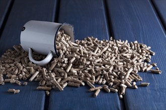 Wood pellets with enamel cup on blue wooden background