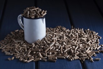 Wood pellets with enamel cup on blue wooden background