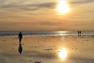 People walking on the mudflats at sunset on the North Sea