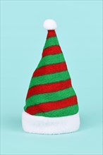 Striped green and red Santa hat on blue background