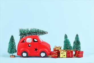 Red car transporting christmas tree snowballs and gift boxes on blue background with